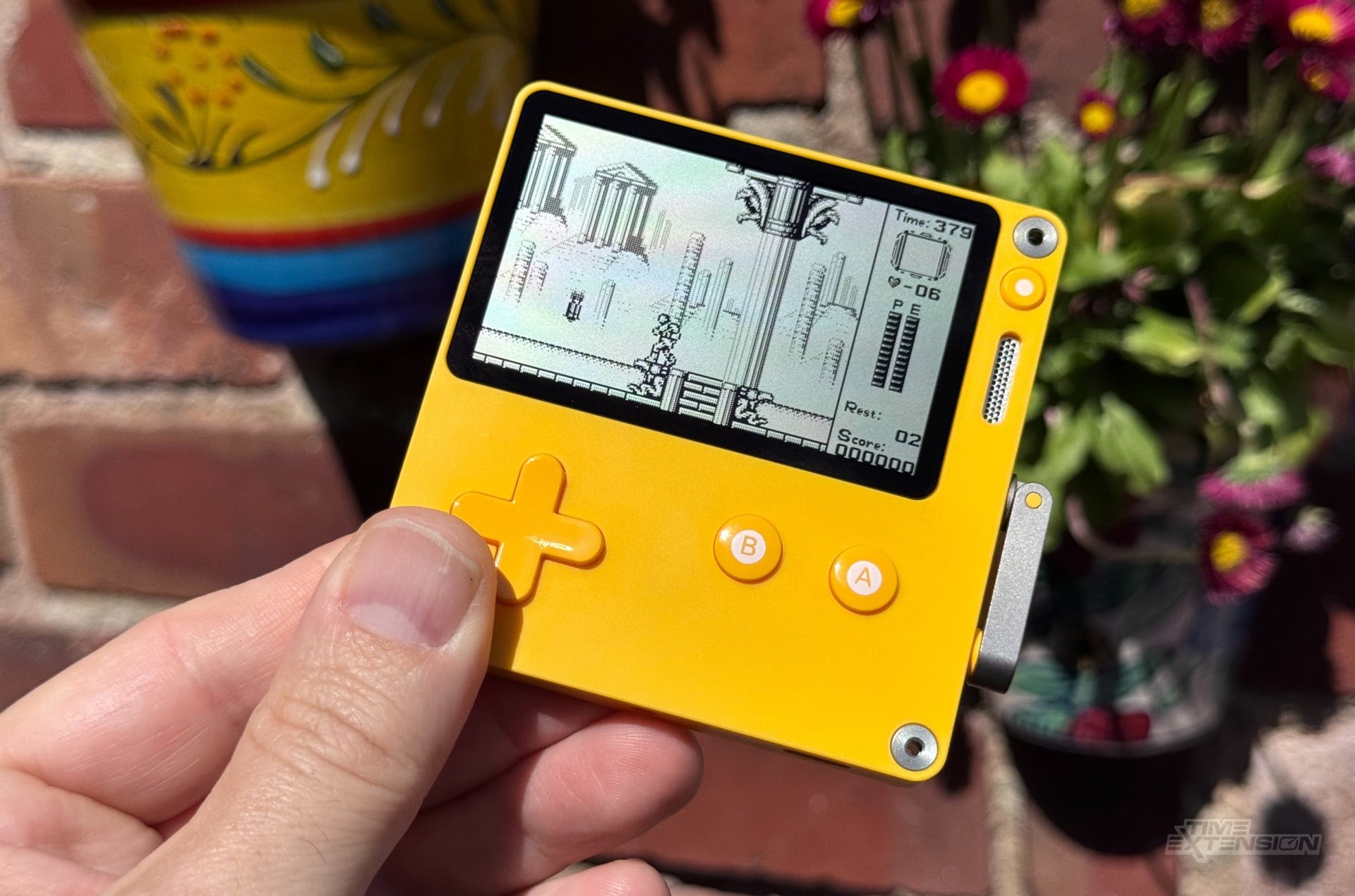 A Playdate handheld shown as a retro gaming device for Game Boy emulation