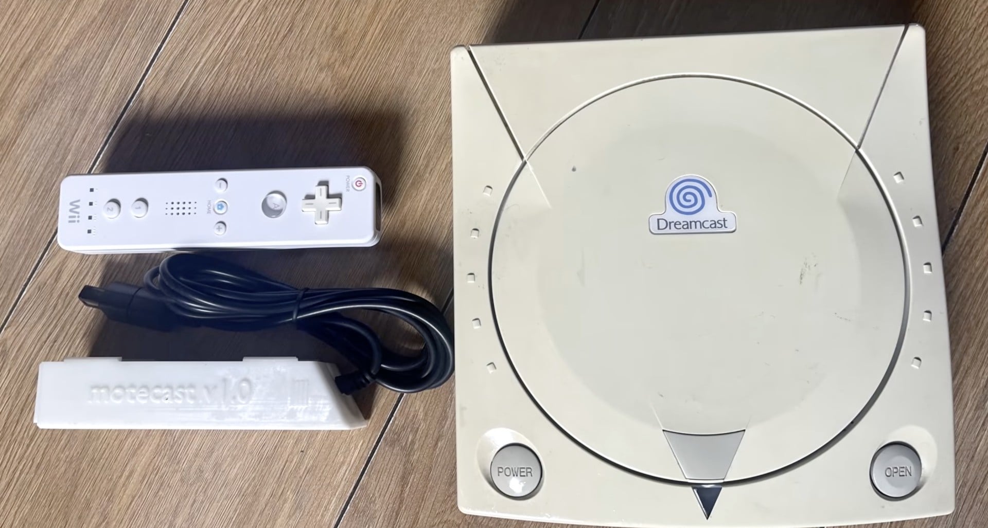 A Sega Dreamcast shown with a Nintendo Wii Remote nearby